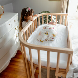 Sister looking at baby who is safely co-sleeping | babybay bedside sleepers