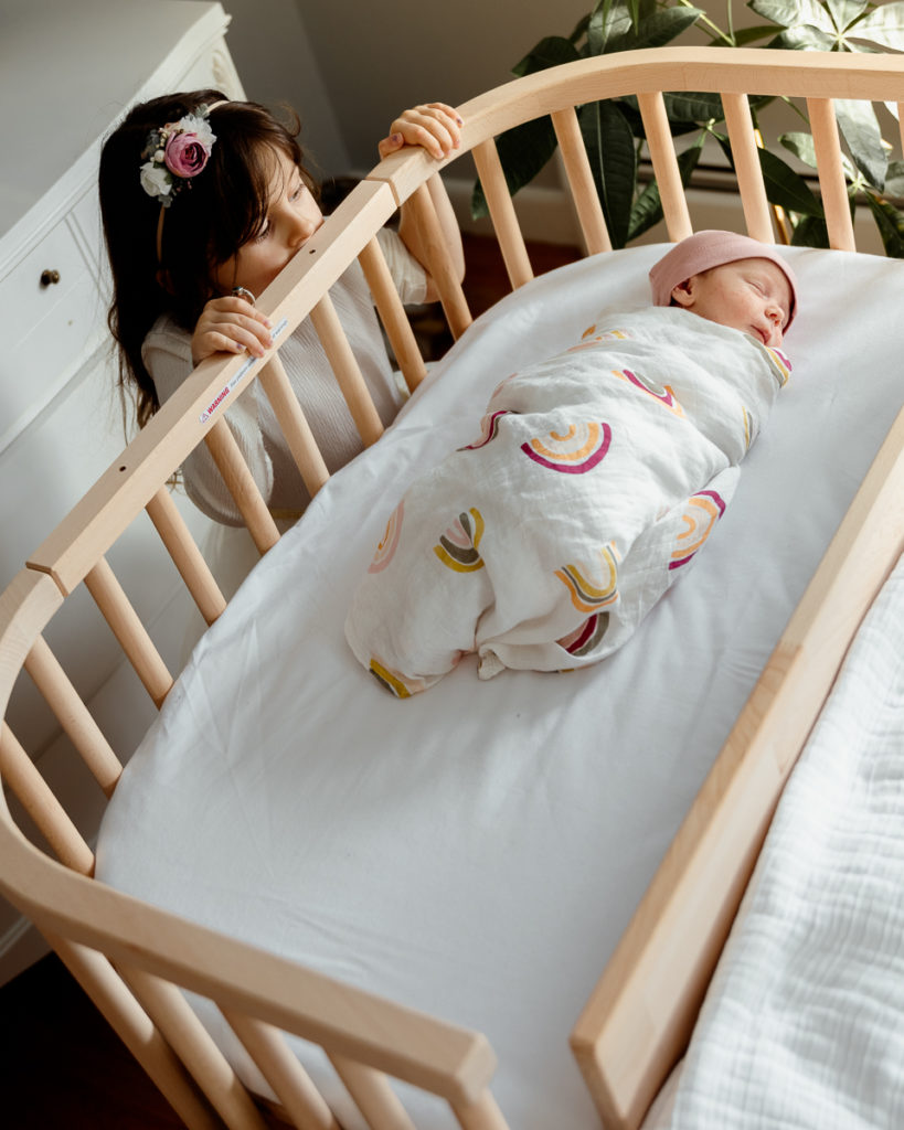 A child looking over a bedside co sleeper where a newborn baby sleeps | babybay bedside bassinet 