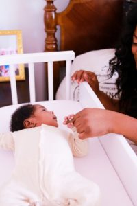 Baby holding finger of parent while lounging in babybay bedside co sleeper | babybay bedside bassinets