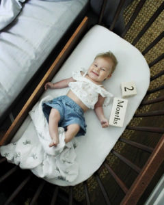 A smiling baby in a bedside co-sleeper at 2 months | babybay bedside sleepers