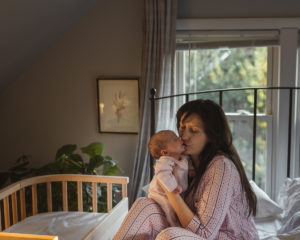 A mother kissing baby while enjoying a bedside sleeper | babybay bedside co-sleepers