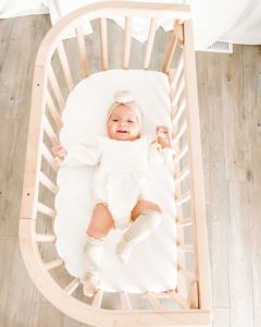 A little girl on comfy sheets for crib | babybay bedside co-sleeper 