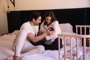 Mom and Dad holding baby next to bedside co sleeper | babybay bedside sleeper