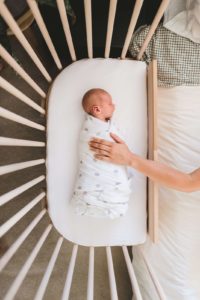 Mother putting a hand on baby crying during sleep | babybay cosleeper cribs