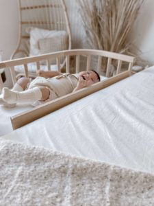 Baby enjoying separate surface co-sleeping with co-sleeper | babybay bedside bassinets