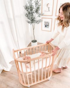 Mother pushing a wooden bassinet with wheels | babybay bedside bassinets