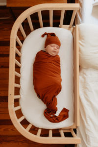 Baby sleeping peacefully in a bedside bassinet| babybay cosleepers