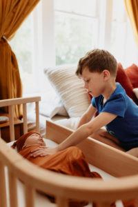 Baby in a bedside co sleeper while big brother watches him dream | babybay cosleepers