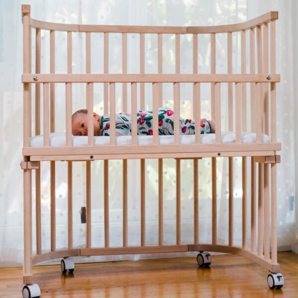 A baby resting in a bedside co-sleeper, an alternative to wooden cribs | babybay bedside co-sleepers