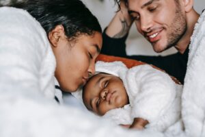 Parents snuggling with baby while considering co-sleeping and bed-sharing | babybay bedside co-sleepers