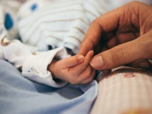 Mother who suffered from pregnancy insomnia holding newborn's hand | babybay cosleeper cribs